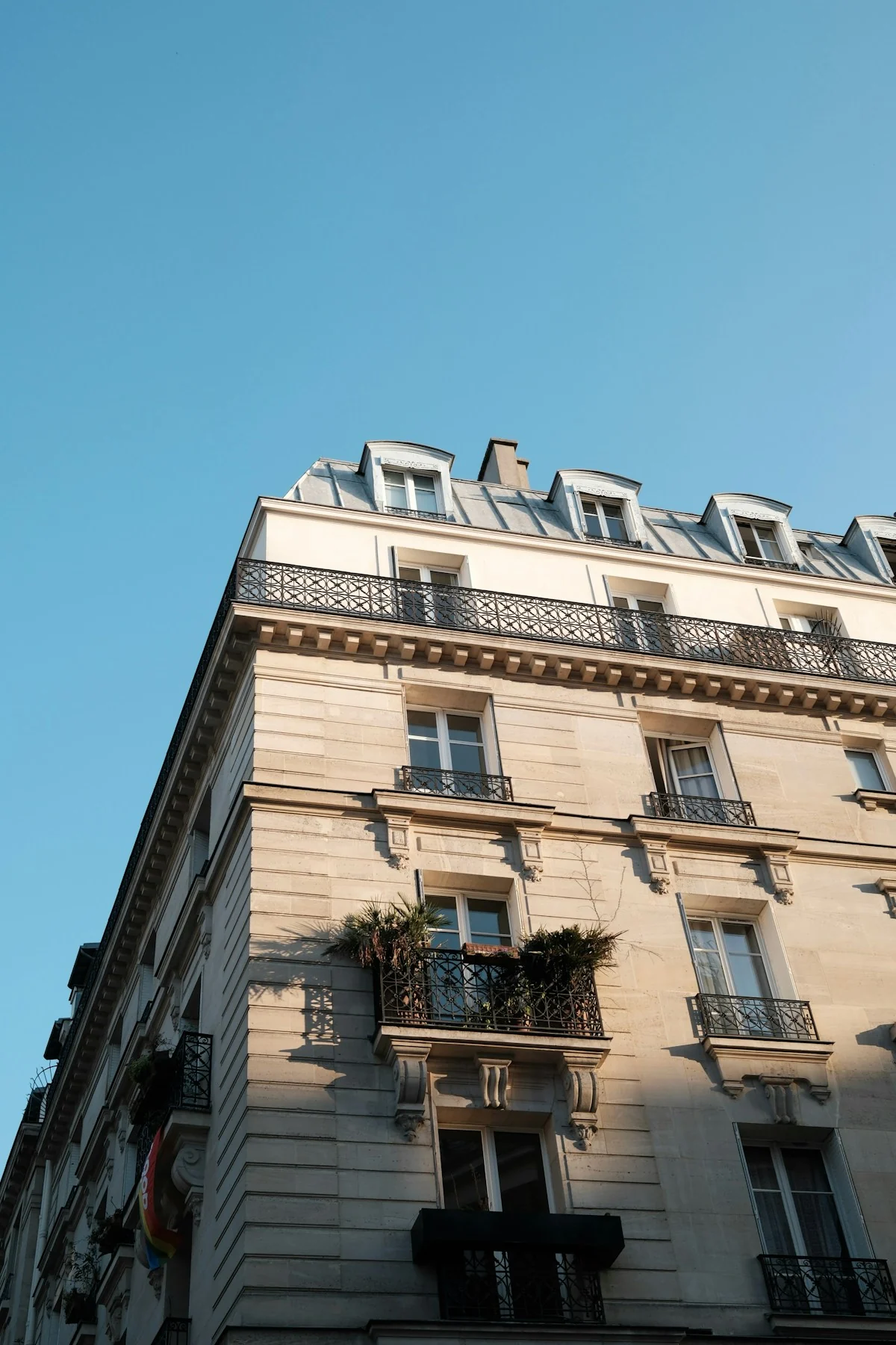 Parisian stone building with wrought-iron balconies beneath a clear blue sky