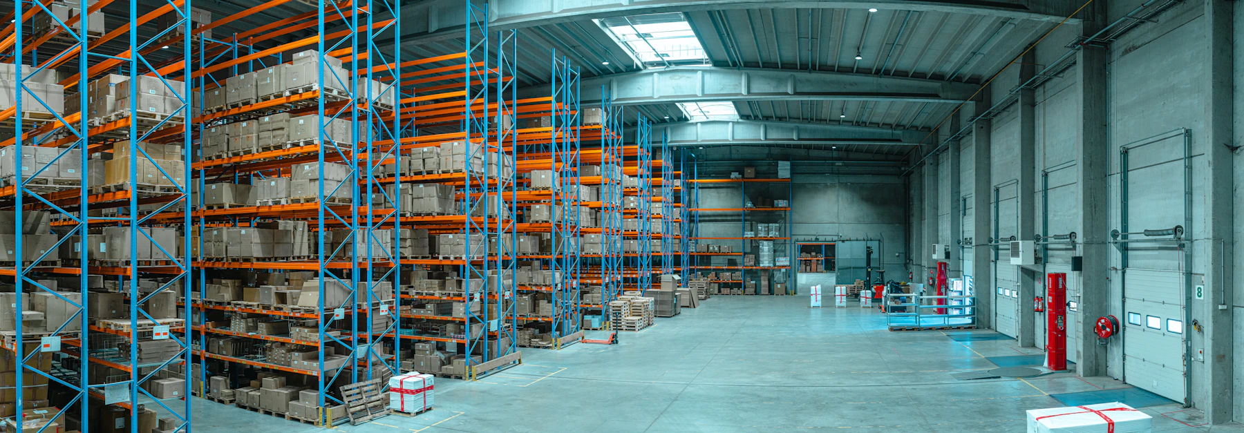 Blue and orange warehouse shelving with plain cardboard boxes beside an open loading area